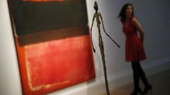 Staff member poses in a gallery near &quot;No. 21 (Red, Brown, Black and Orange)&quot; by Rothko and &quot;Chariot&quot; by Giacometti at Sotheby's auction house in London