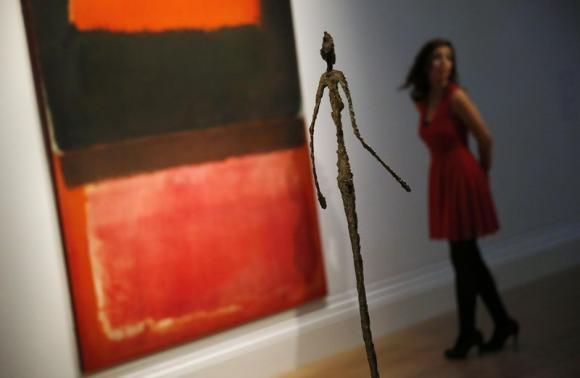 Staff member poses in a gallery near &quot;No. 21 (Red, Brown, Black and Orange)&quot; by Rothko and &quot;Chariot&quot; by Giacometti at Sotheby's auction house in London