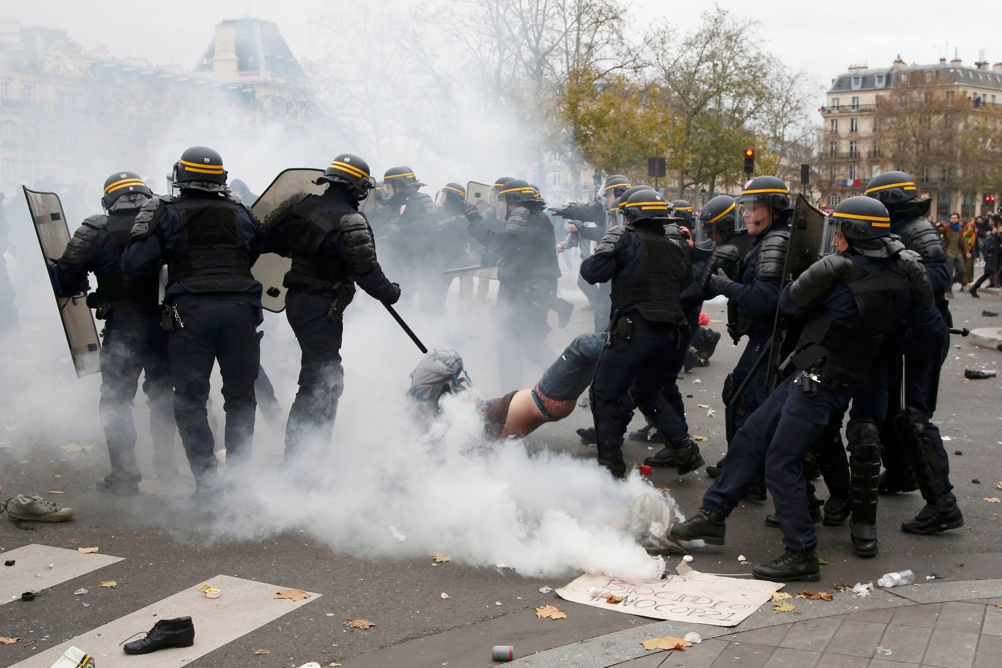 French CRS riot police apprehend a demonstrator during clashes near the Place de la Republique after the cancellation of a planned climate march  ahead of the World Climate Change Conference 2015 in P