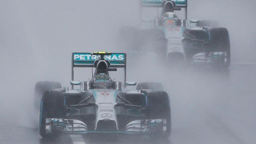 Mercedes Formula One driver Nico Rosberg of Germany leads team mate Lewis Hamilton of Britain behind a safety car (unseen) as they start the first lap of the rain-affecte