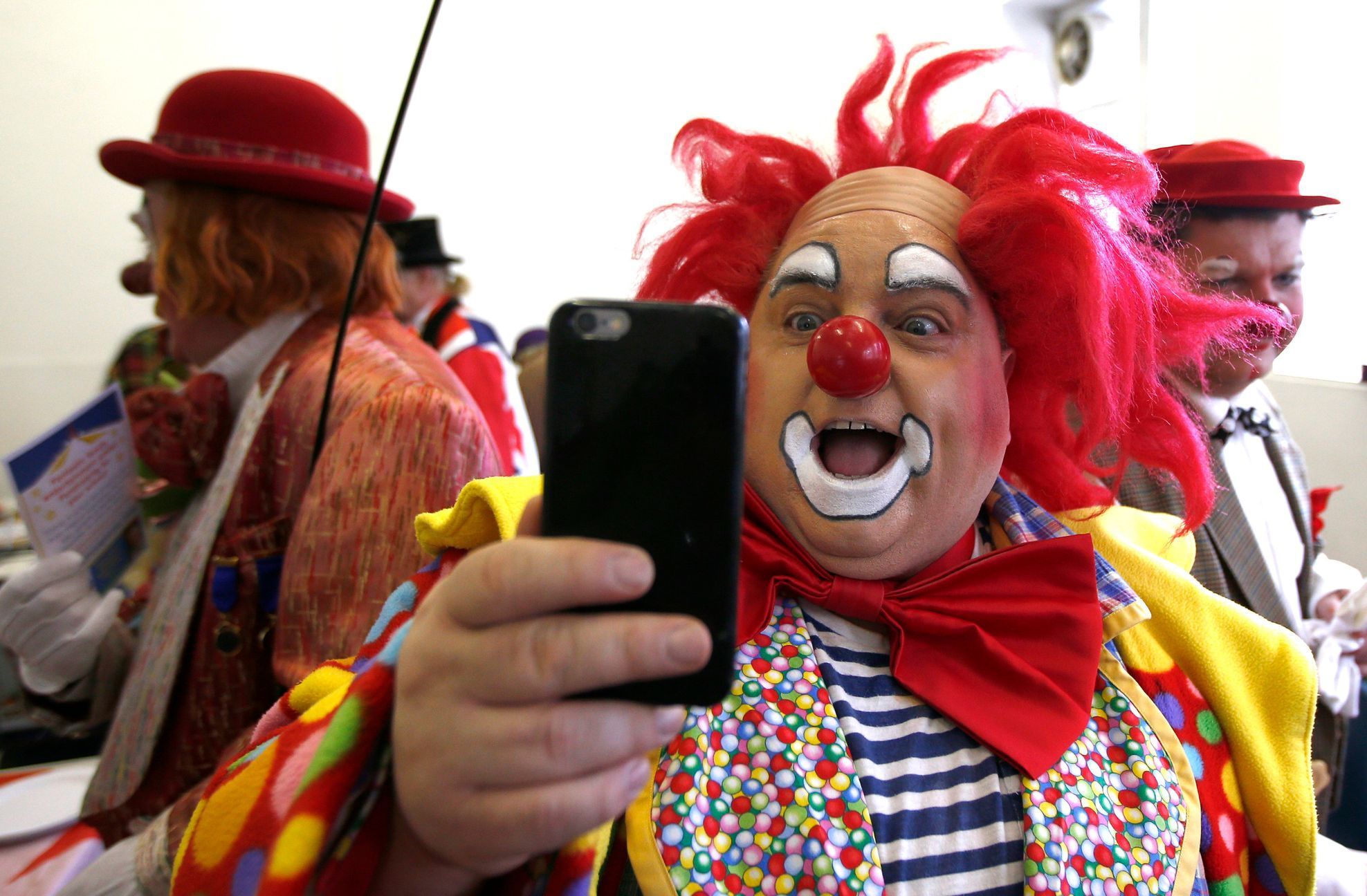 A clown takes a selfie at the All Saints Church hall before the Grimaldi clown service in Dalston, north London