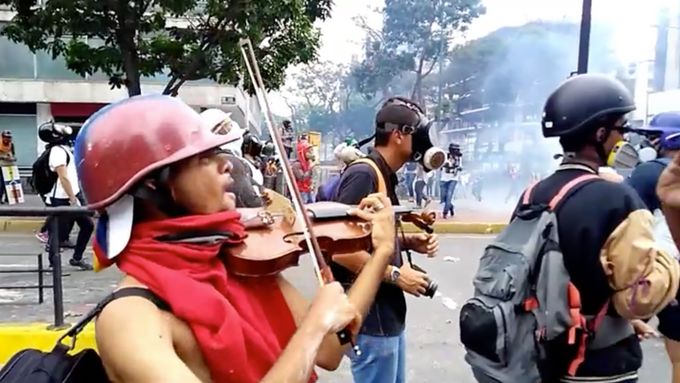 Muž hraje uprostřed zuřící venezuelské demonstrace na housle.