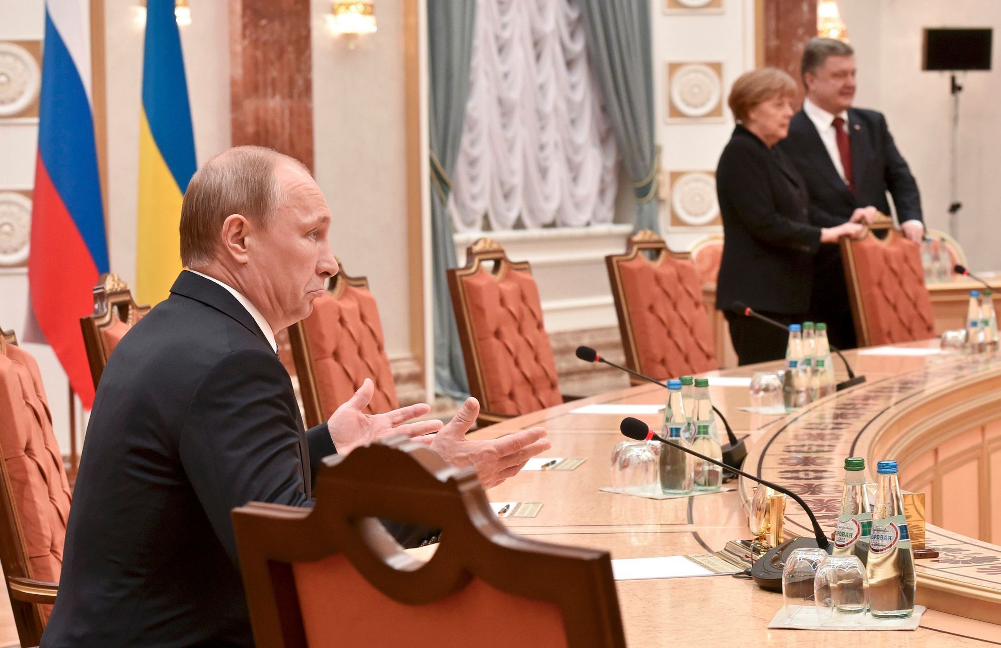 Vladimir Putin na jednání v Minsku (v pozadí Angela Merkelová a Petro Porošenko)