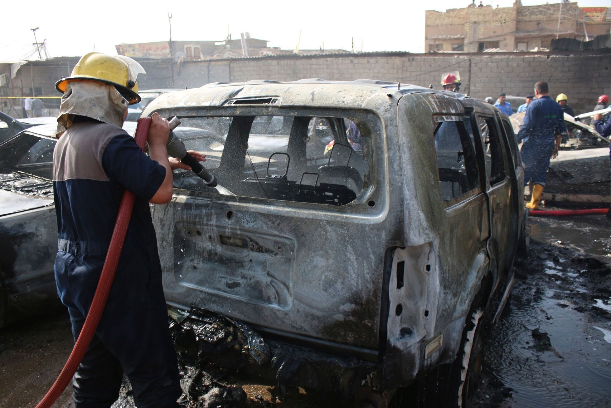 A firefighter hoses down a vehicle after a car bomb attack in Basra, southeast of Baghdad
