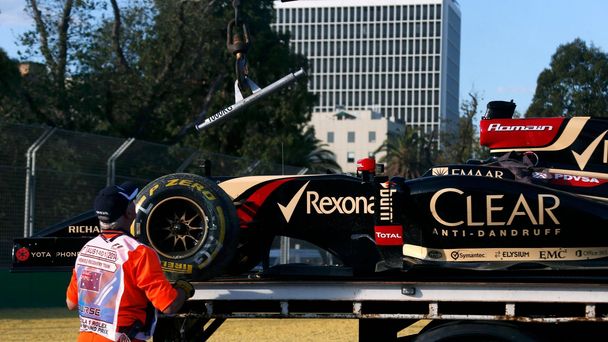 Workers load the car of Lotus Formula One driver Grosjean of France onto a truck during the second practice session of the Australian F1 Grand Prix in Melbourne