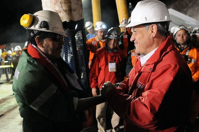 Chilský prezident Sebastián Piňera vítá na zemském povrchu předáka zasypaných horníků.