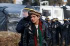 Francouzský policista odvádí Afghánce z tábora v Calais.