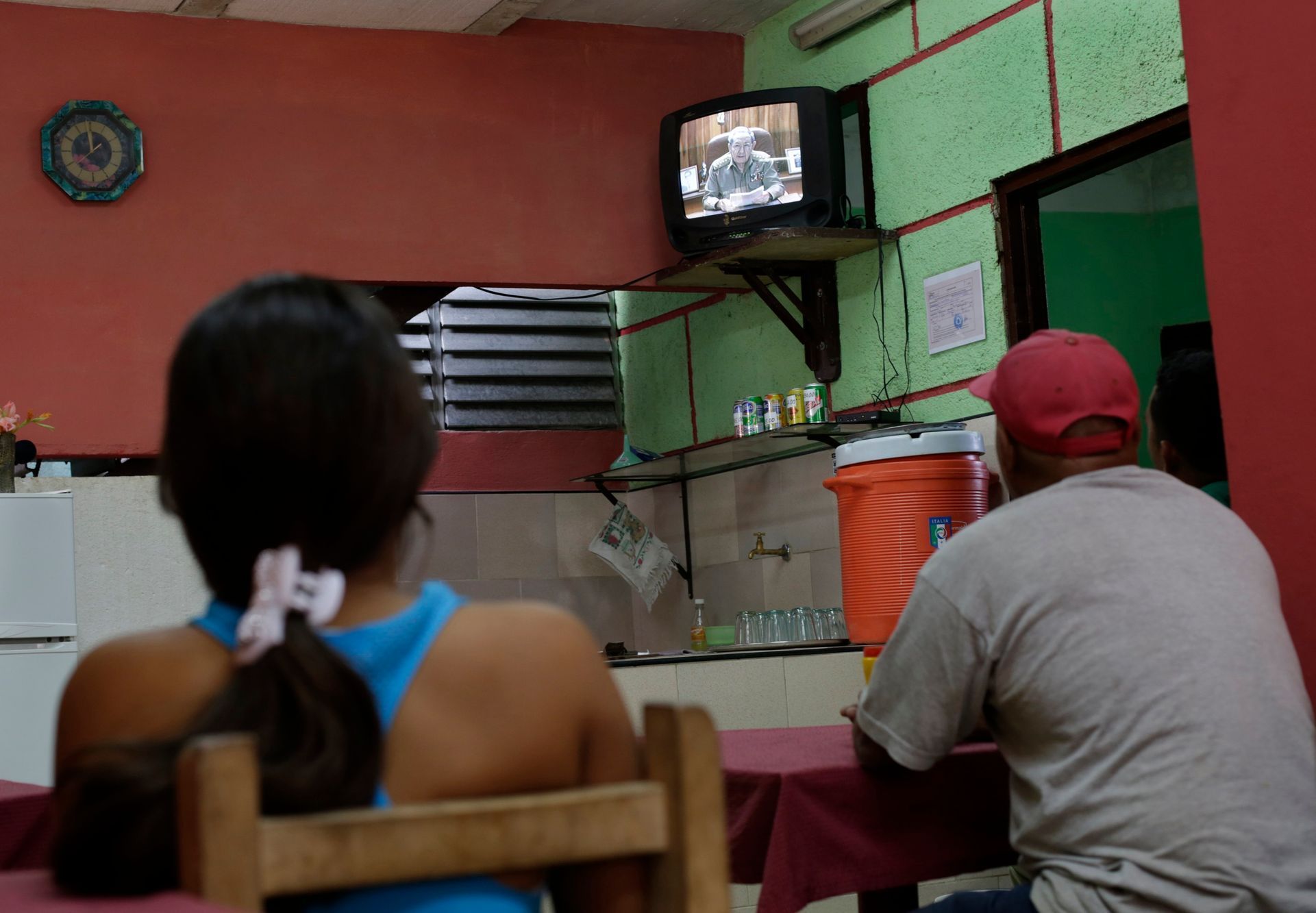 People watch television footage showing Cuba's president Castro speaking during a state television broadcast in a private restaurant in Havana