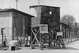 Toto je snímek z května 1945: Strážní věž tábora se skupinkou osvobozených vězňů.