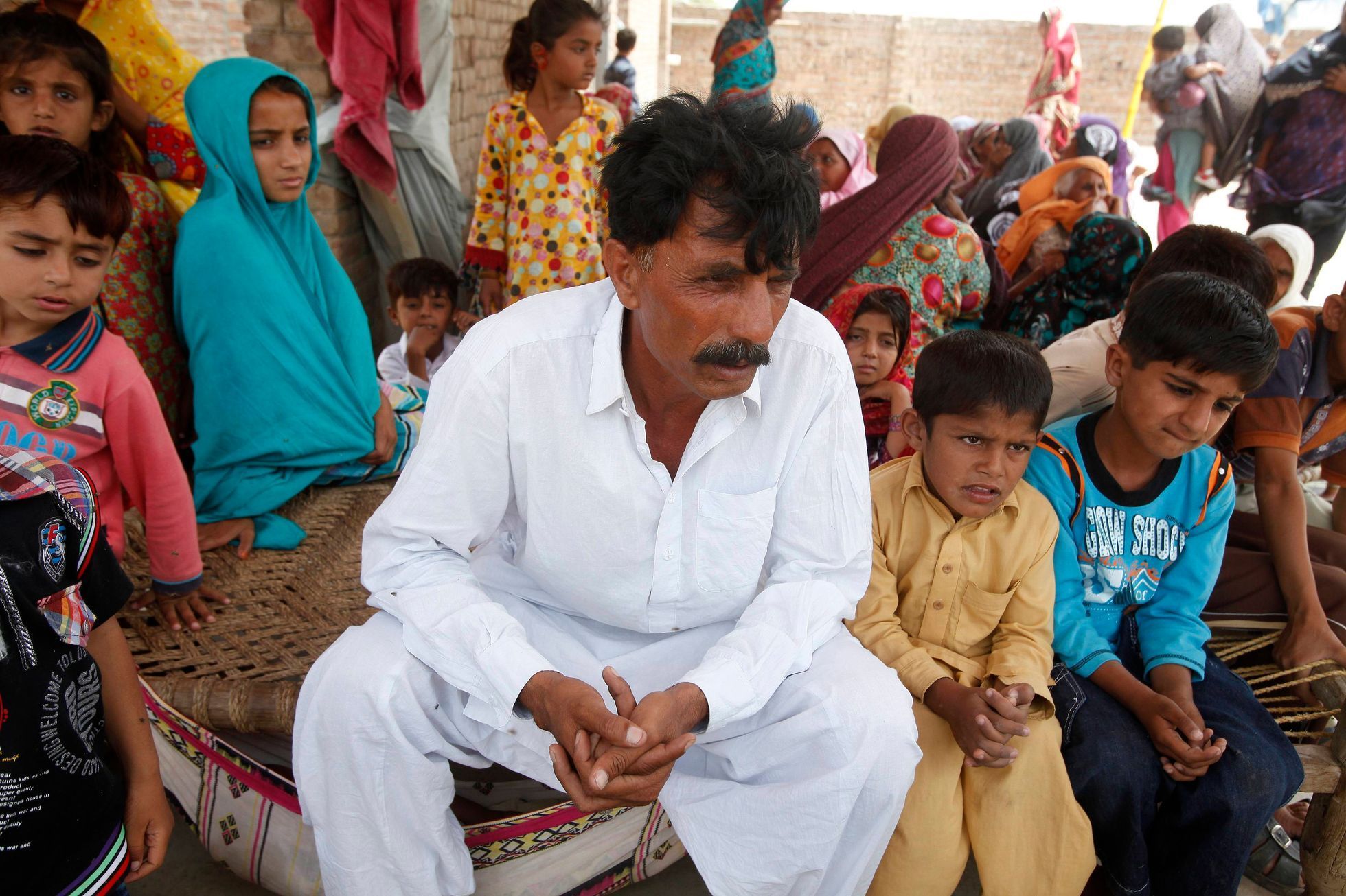 Iqbal sits with his family members at his residence in a village in Moza Sial
