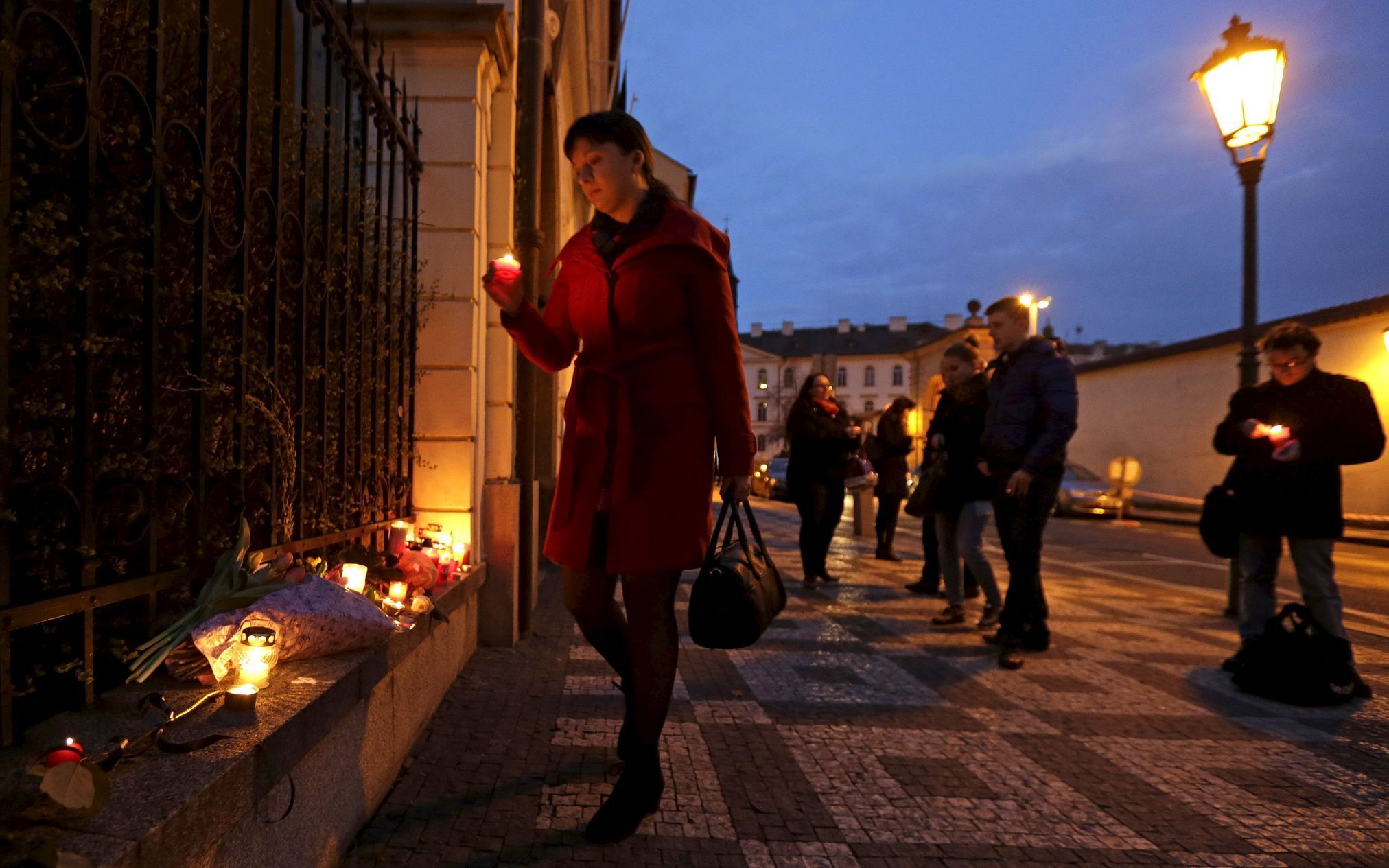 Lidé před belgickou ambasádou v Praze zapalují svíčky.