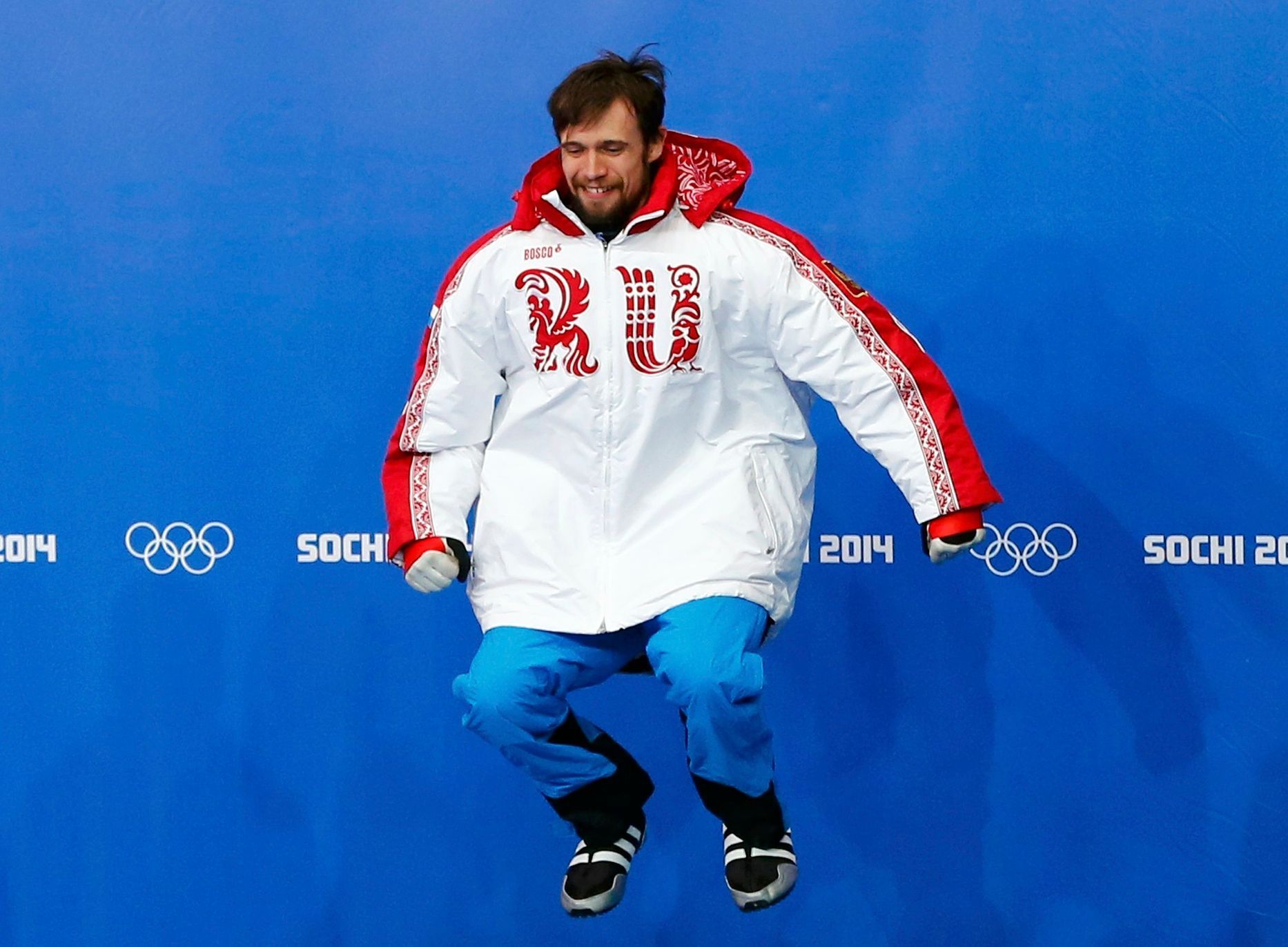 Russia's Alexander Tretiakov jumps on the podium at the flower ceremony after winning the men's skeleton event at the 2014 Sochi Winter Olympics