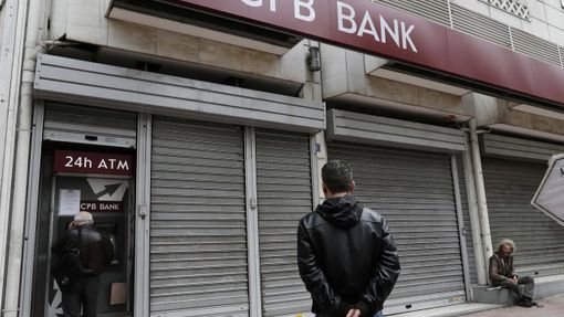 Lidé vybírají peníze z bankomatu zavřené pobočky kyperské banky Cyprus Popular Bank (CPB) v Athénách v Řecku.
