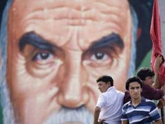 Mladící stojí v Teheránu před obřím billboardem s tváří vůdce islámské revoluce ajatolláha Chomejního.
