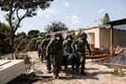 Izraelští vojáci v kibucu Kfar Aza vynášejí mrtvé tělo.