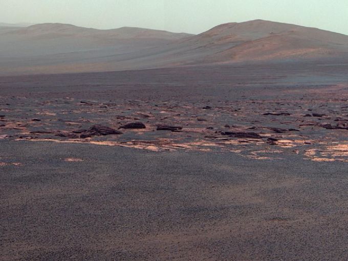 West Rim of Endeavour Crater on Mars (False Color) A portion of the west rim of Endeavour crater sweeps southward in this color view from NASA's Mars Exploration Rover Opportunity. This crater -- with a diameter of about 14 miles (22 kilometers) -- is more than 25 times wider than any that Opportunity has previously approached during the rover's 90 months on Mars. The view is presented in false color to emphasize differences among materials in the rocks and the soils. This view combines exposures taken by Opportunity's panoramic camera (Pancam) on the 2,678th Martian day, or sol, of the rover's work on Mars (Aug. 6, 2011) before driving on that sol. The subsequent Sol 2678 drive covered 246 feet (75.26 meters), more than half of the remaining distance to the rim of the crater. Opportunity arrived at the rim during its next drive, on Sol 2681 (Aug. 9, 2011). Endeavour crater has been the rover team's destination for Opportunity since the rover finished exploring Victoria crater in August 2008. Endeavour offers access to older geological deposits than any Opportunity has seen before. The closest of the distant ridges visible along the Endeavour rim is informally named "Solander Point." Opportunity may investigate that area in the future. The rover's first destination on the rim, called "Spirit Point" in tribute to Opportunity's now-inactive twin, Spirit, is to the left (north) of this scene. The lighter-toned rocks closer to the rover in this view are similar to the rocks Opportunity has driven over for most of the mission. However, the darker-toned and rougher rocks just beyond that might be a different type for Opportunity to investigate. The ground in the foreground is covered with iron-rich spherules, nicknamed "blueberries," which Opportunity has observed frequently since the first days after landing. They are about 0.2 inch (5 millimeters) or more in diameter. Images combined into this view were taken through three different Pancam filters admitting light with wavelengths centered at 753 nanometers (near infrared), 535 nanometers (green) and 432 nanometers (violet). Seams have been eliminated from the sky portion of the mosaic to better simulate the vista a person standing on Mars would see. Image Credit: NASA/JPL-Caltech/Cornell/ASU