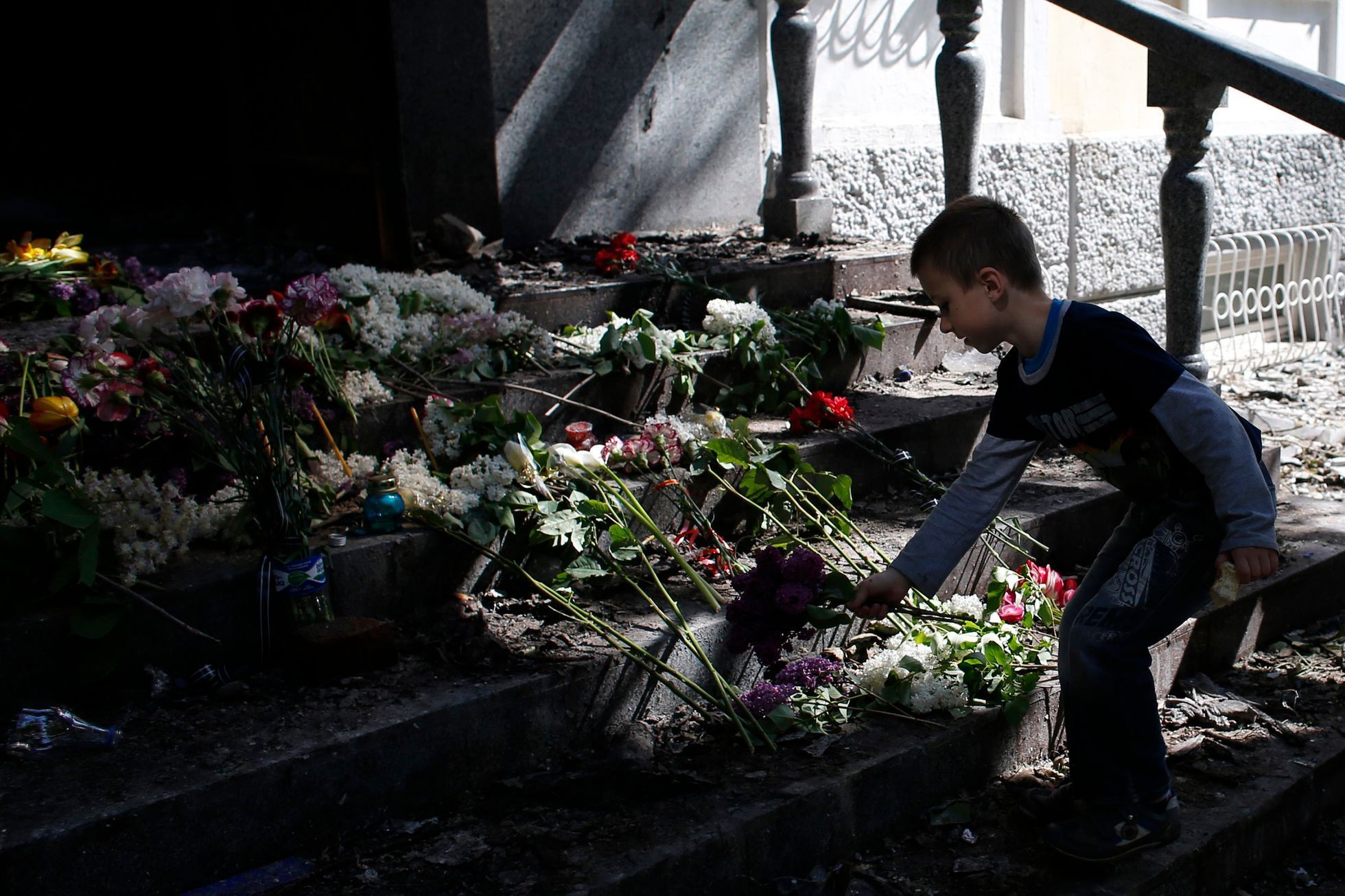A boy places flowers in front of a gutted police station building in Mariupol