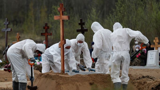 Hrobníci ukládají do země rakev s ostatky jedné z oběti nemoci covid-19 v Petrohradu.
