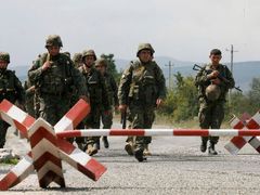 Gruzínští vojáci přecházejí skrz zátarasy opuštěného stanoviště ruských mírových jednotek v Jižní Osetii.