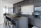 Kuchyně má úložné prostory, které tvoří celou jednu stěnu. Zabudovaná vinotéka v ocelovém rámu ladí s barem, kde se pohodlně usadí až šest osob.