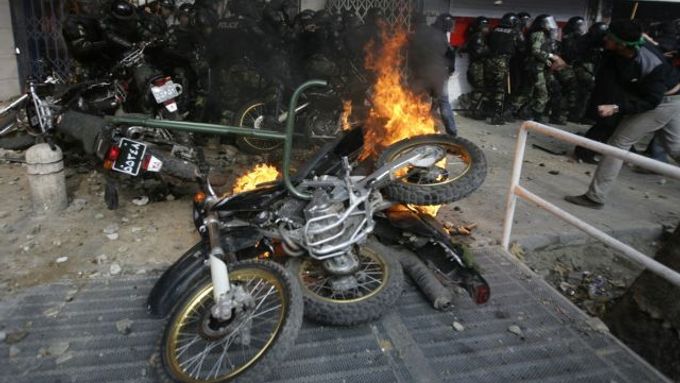 Zapálené motorky v ulicích Teheránu. Na motorkách jezdí tzv. basídžové. členové milic, kteřé útočí na demonstranty tyčemi a řetězy.