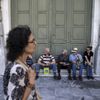 People, most of them pensioners, sit outside a closed National Bank branch at the bank's headquarters in Athens