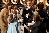 Reřisér a producent Steve McQueen oslavuje vítězství filmu 12 let v řetězech ve společnosti oscarové herečky Lupity Nyong'o a dalších členů štábu - například herce Benedicta Cumberbatche.