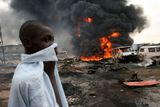 Chlapec na spáleništi poblíž nigerijského Lagosu si zakrývá tvář. V tomto místě se vzňal ropovod, o život přišlo podle agentury Reuters až 500 lidí. Dýchat se dalo jen s obtížemi.