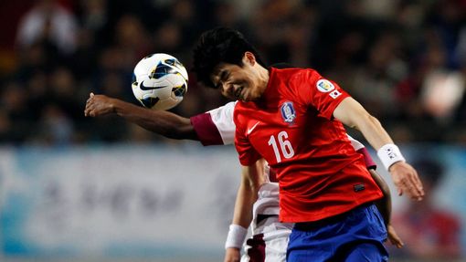 Korea - Katar (kvalifikace MS 2014) -  Ki Sung-Yueng a Khalfan Ibrahim bojují o míč.