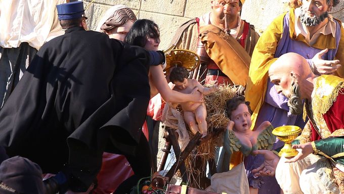 Vatikánský četník se snaží aktivistce hnutí Femen zabránit, aby odnesla Ježíška z jesliček.