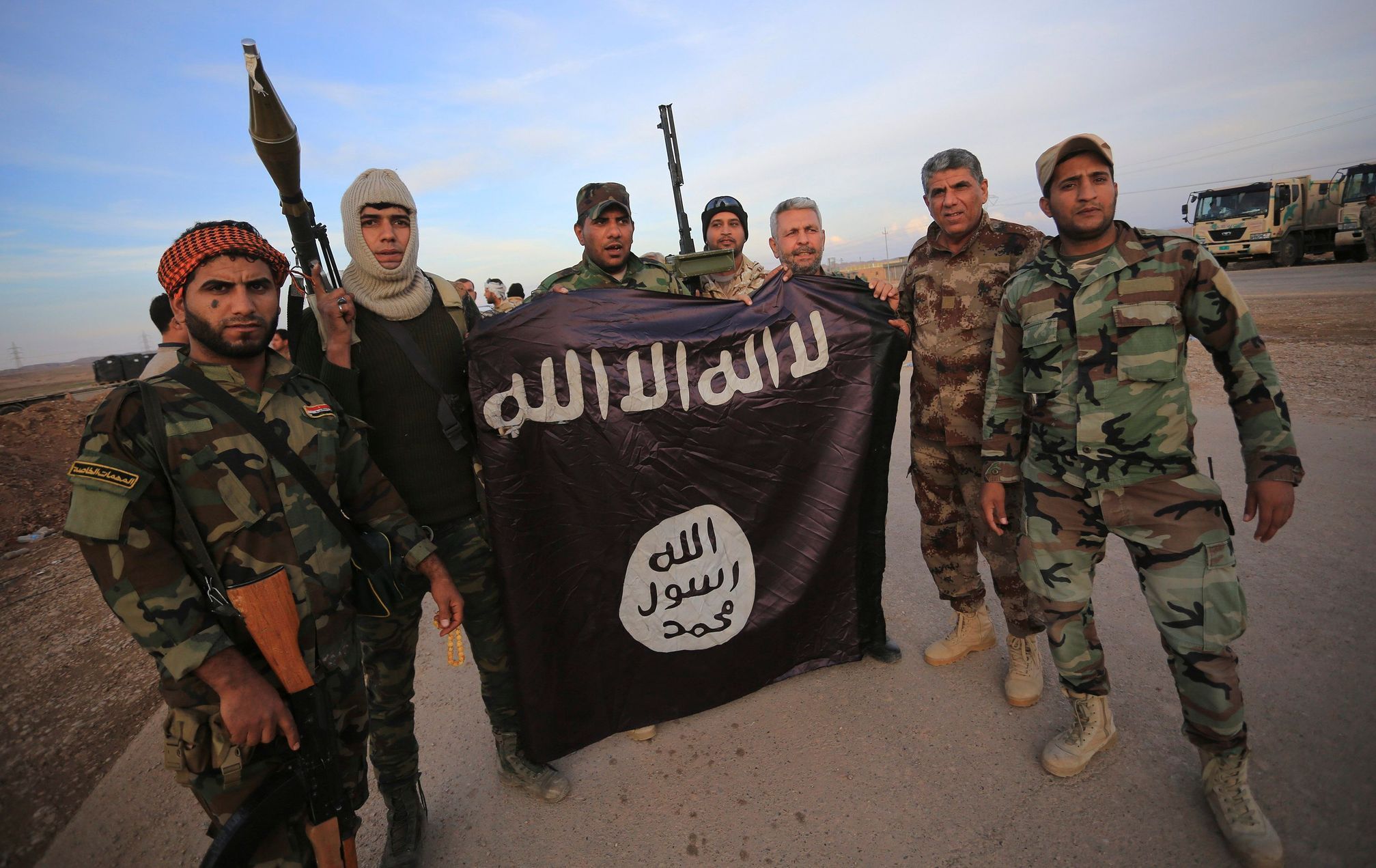 Iráčtí šíité s vlajkou, kterou vzali bojovníkům Islámského státu.