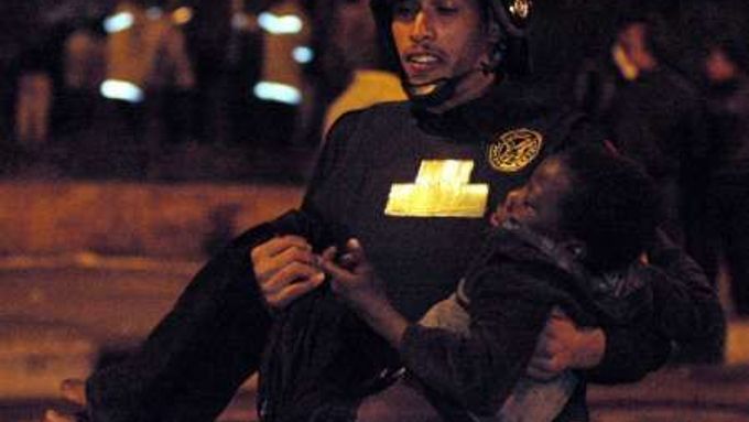 Egyptský policista odnáší súdánského chlapce, který byl zraněn při střetu u imigrantského tábora Káhiře.
