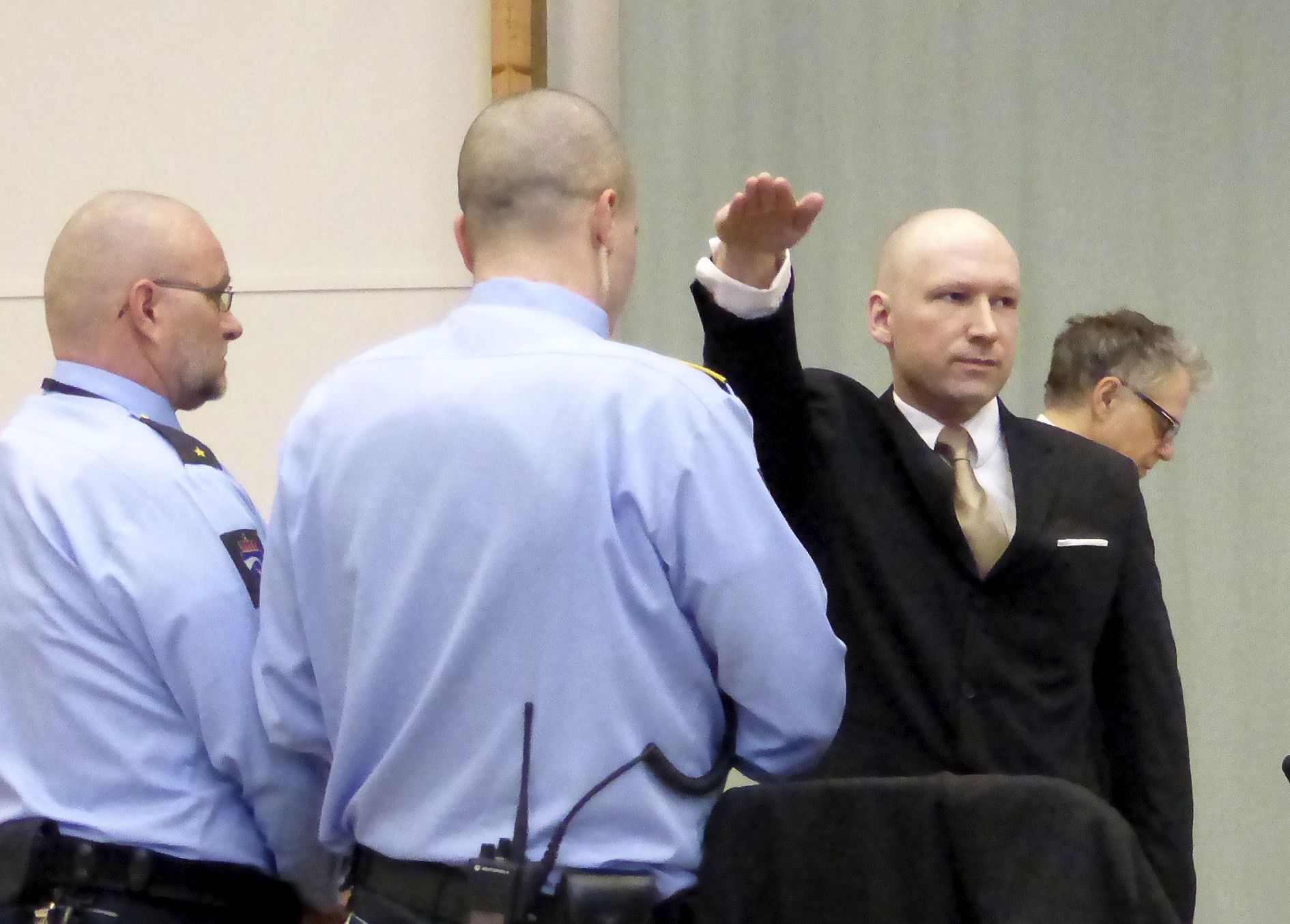 Breivik hajluje Mass killer Anders Behring Breivik raises his arm in a Nazi salute as he enters the court room in Skien prison