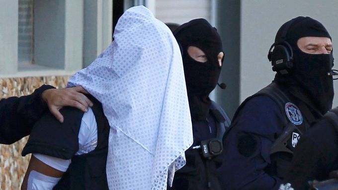 Policie eskortuje muže, který se přiznal k atentátu v továrně poblíž Lyonu, 28. června.