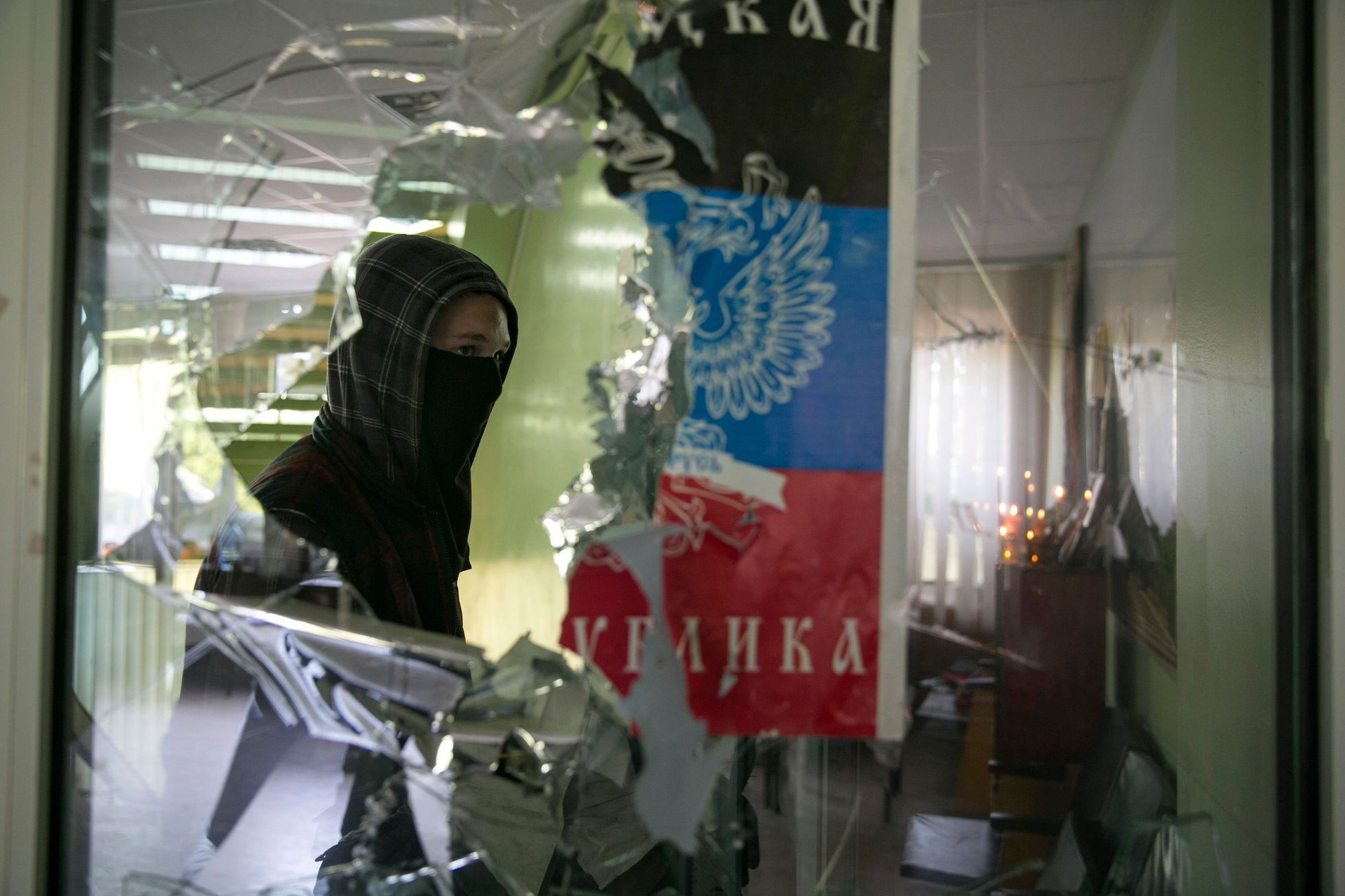 Proruský separatista prochází kolem rozbitého okna na radnici v Mariupolu.