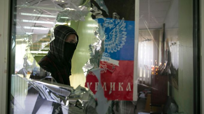 Proruský separatista prochází kolem rozbitého okna na radnici v Mariupolu.