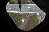 Pohled z vrtulníku. Skříň zavěšená pod vrtulníkem nad nuselským mostem.