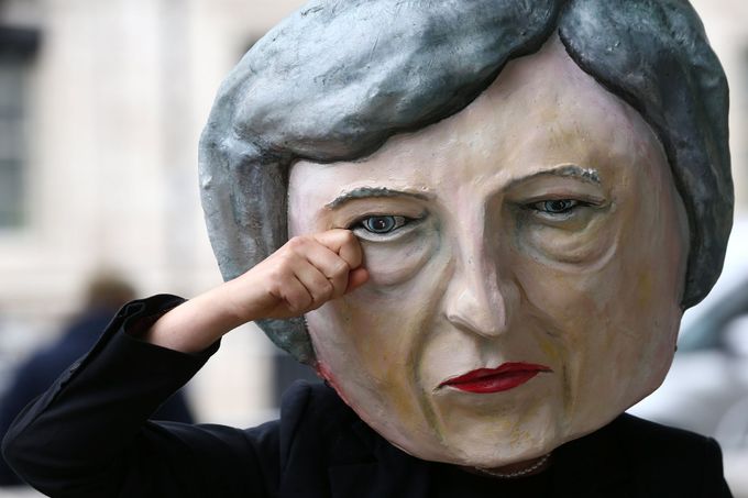 Muž s maskou Theresy Mayové stojí den po volbách před sídlem premiérky v londýnské Downing Street.