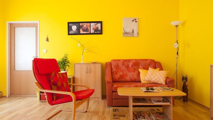 Dvoumístná sedačka, křeslo, konferenční stolek a dvě žluté stěny - obývák "průměrného" Čecha.