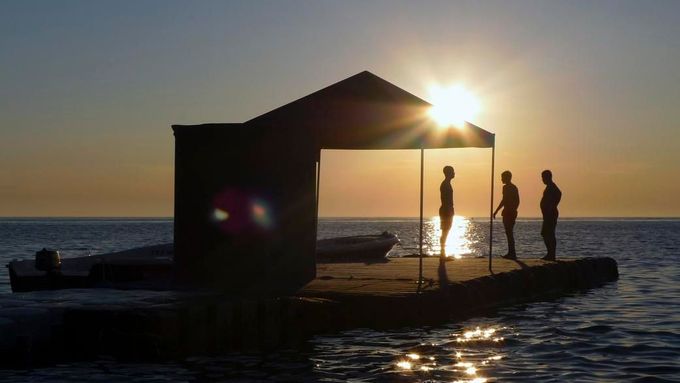 Turisté při západu slunce na pontonu v chorvatském městě Pula.