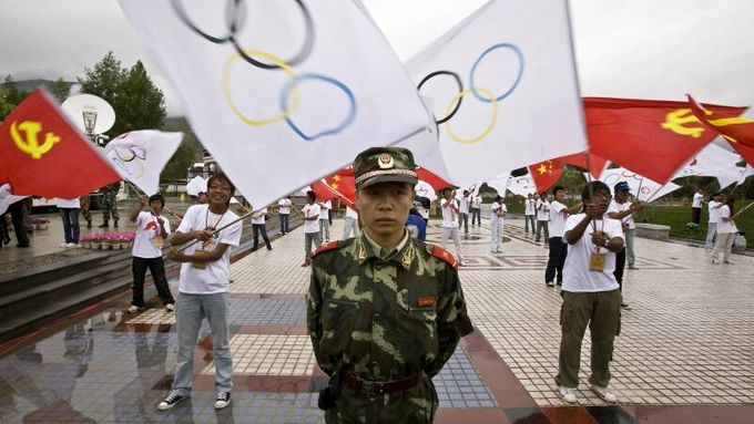 A People's Liberation Army (PLA) soldier stand guards as organized participants wave flags during the opening ceremony of the Olympic torch relay in Lhasa, Tibet June 21, 2008. REUTERS/Nir Elias (CHINA) (BEIJING OLYMPICS 2008 PREVIEW)