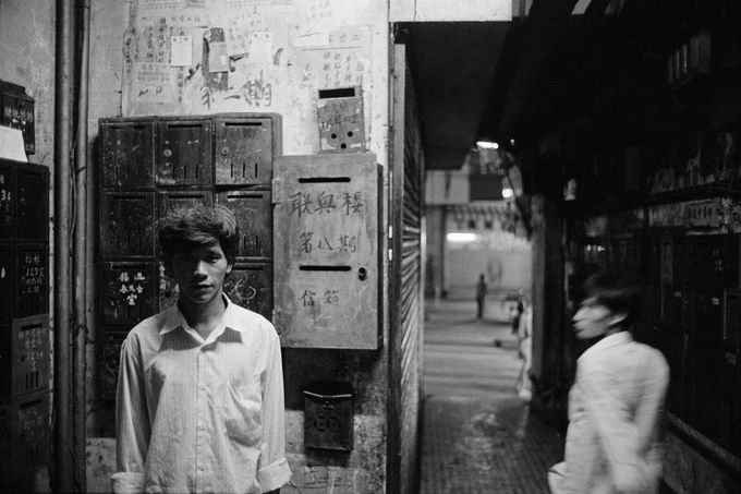 Lidé v uličce chudinské čtvrťi Walled City v Hongkongu. Snímek z konce 80. let 20. století.