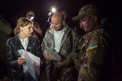 Zástupkyně proruských rebelů (vlevo) a zástupci ukrajinských vládních síl (uprostřed a vpravo) se domlouvají před výměnou.