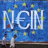 Řecko Men walk by fresh anti-EU graffiti in Athens, Greece