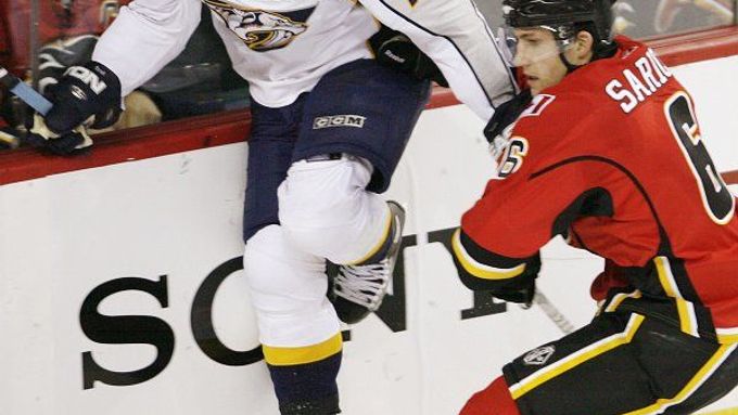 Martin Erat z Nashville Predators se snaží přeskočit hůl Coryho Saricha z Calgary Flames.