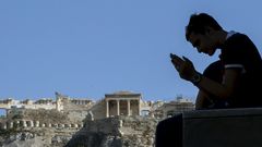 Muž se dívá v Aténách do mobilu. Sleduje zprávy ze summitu v Bruselu?