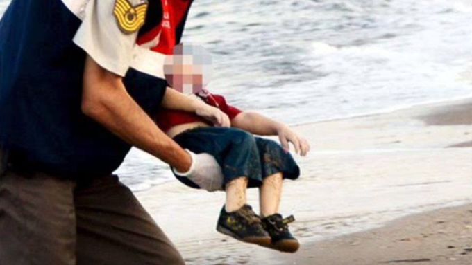 Turecký policista odnáší tělo utonulého chlapce.