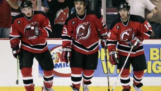 Hokejisté New Jersey (zleva Zach Parise, Scott Gomez a Brian Gionta) se radují z branky v síti Caroliny.