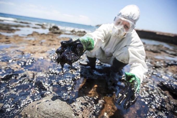 A volunteer collects fuel oil from rocks at the "Muelle Viejo" beach in Gran Canaria in Spain's Canary Islands
