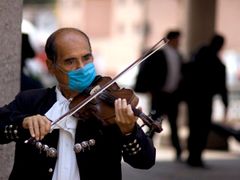 Muž s rouškou hraje na housle - Garibaldiho náměstí v Mexiko City.